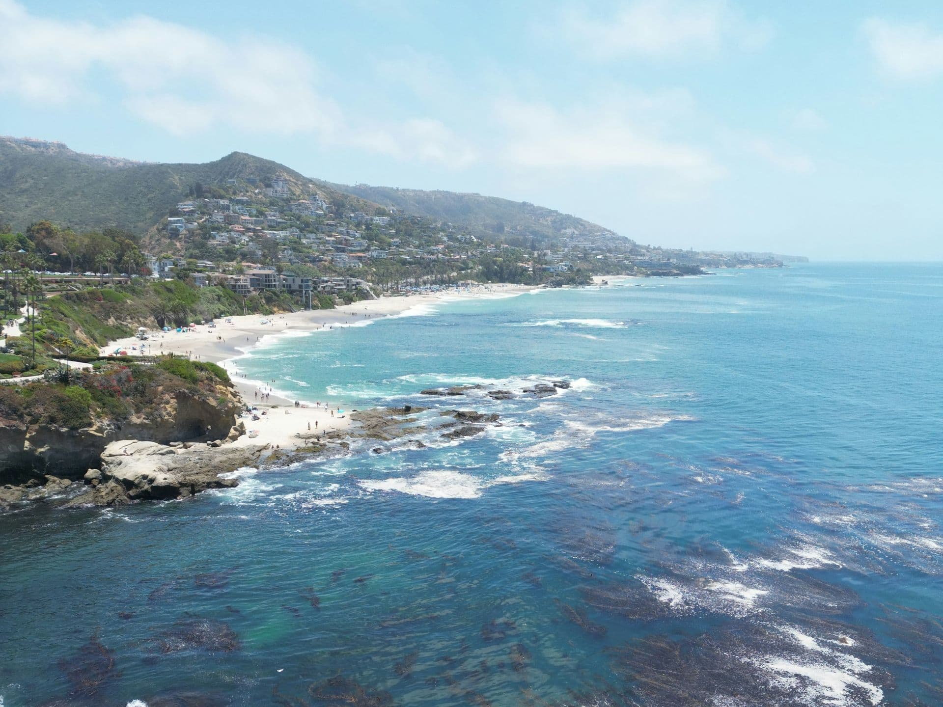Aerial view of a rocky coastline, a sandy beach and clear blue-green ocean