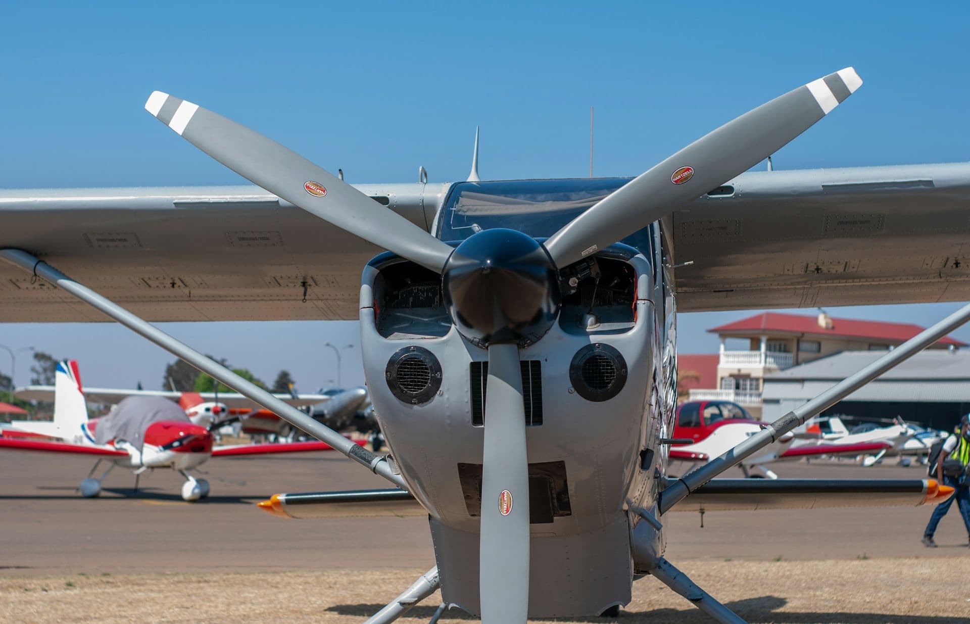 Front view of a small high-wing airplane’s propeller and cowling on a sunny ramp